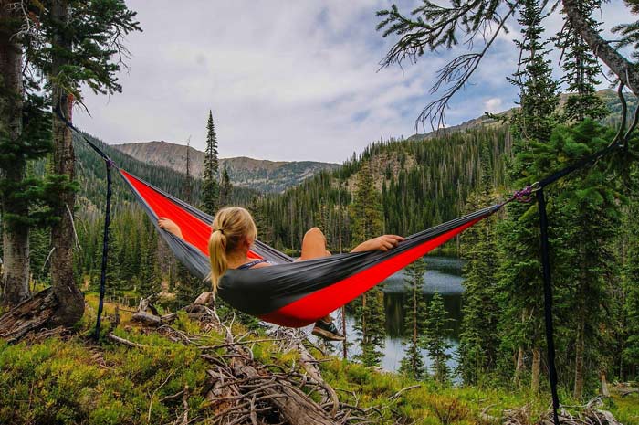 woman in hammock looking out at wooded lake